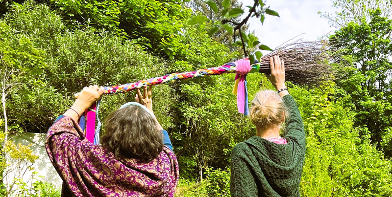 Zwei Frauen halten einen Hexenbesen in die Luft